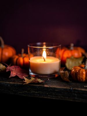 Generated still: a lit candle with small pumpkins